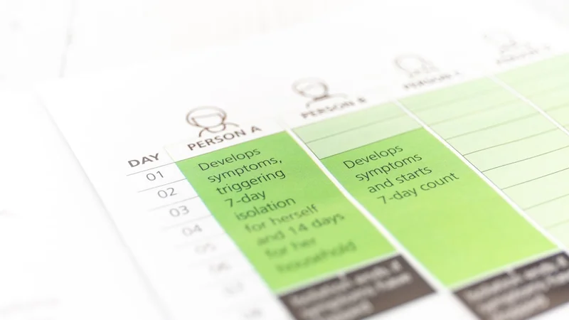 Person an einem sauberen, organisierten Schreibtisch, die bei Morgenlicht in einem Tagebuch schreibt