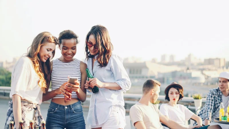Zwei Freunde sitzen auf einer Parkbank, lachen zusammen im natürlichen Nachmittagslicht, unbefangen und echt