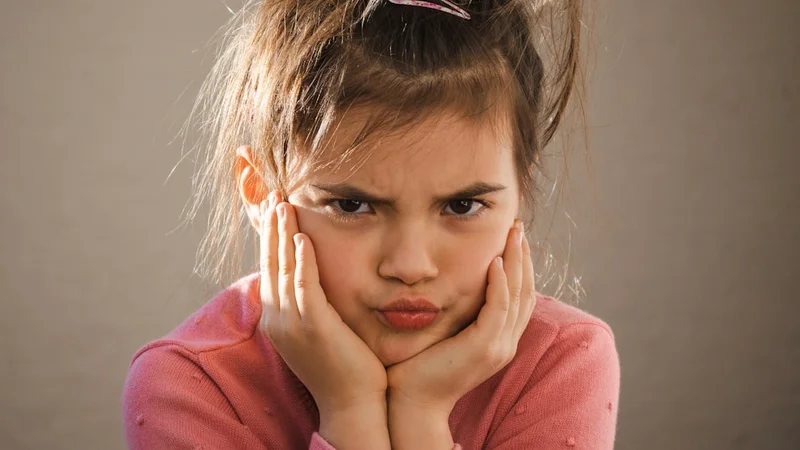 A parent sitting calmly on the floor next to a child who is visibly upset, offering presence without speaking