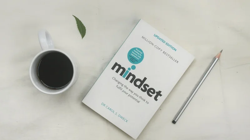 A handwritten notebook page showing common fixed-mindset statements "I'm not good at X" with arrows pointing to reframed versions "I haven't developed X yet", clean desk, morning light