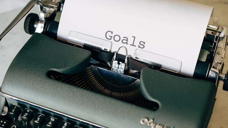 A clean desk calendar showing September, with a pen marking a single date and a blank goal-planning notebook open beside it