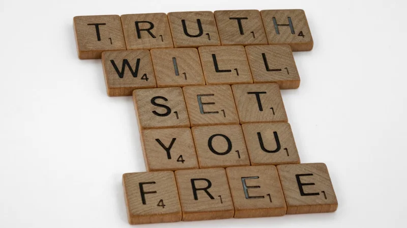 A person standing at a large window in morning light, posture open and calm, uncluttered room behind them