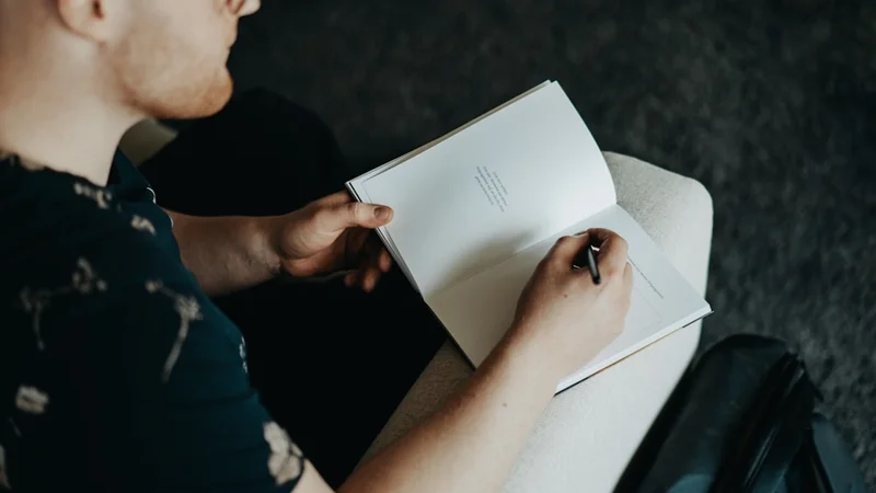 open notebook with handwritten columns labeled "Impression" and "Evidence," pen resting on the page, warm desk lighting