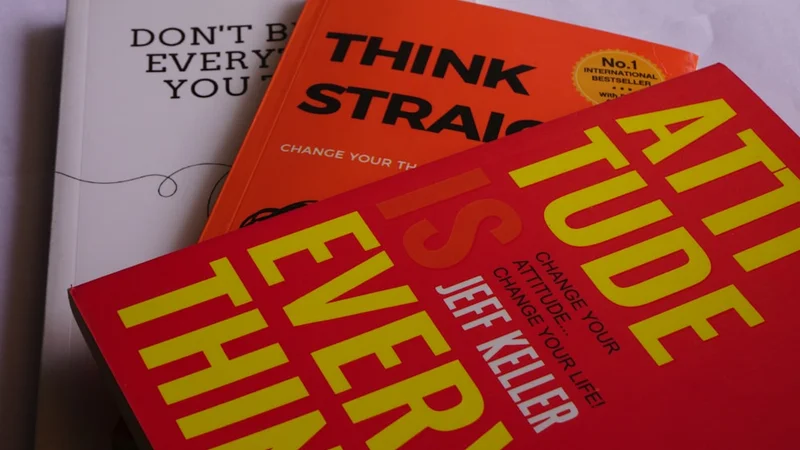 minimal desk with a single open notebook showing a short handwritten book summary, a pen resting across the page, and two nonfiction books stacked nearby in soft focus