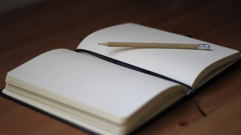 Open notebook on a desk with handwritten notes, morning light, coffee nearby