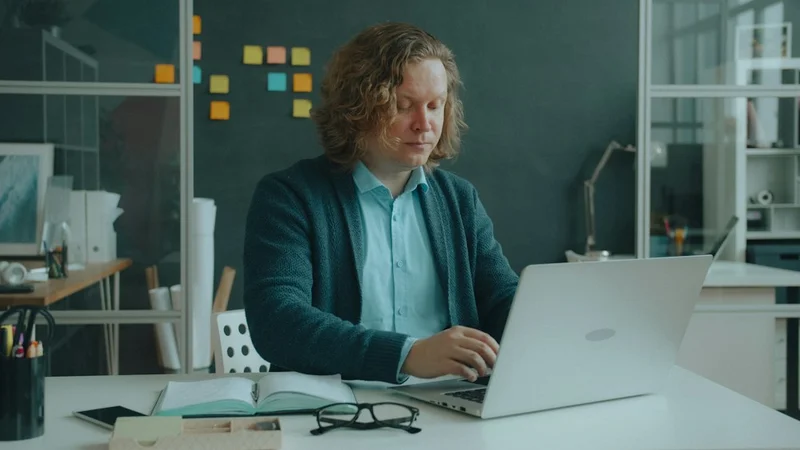 person sitting at a clean desk with a complex project open on a laptop, looking focused and calm under visible deadline pressure, natural window light, keyword: stress mindset enhancing challenge state