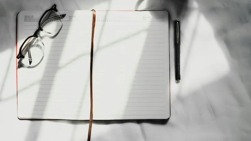 open guided journal on a clean desk with handwritten daily entries visible, pen resting across the page, warm morning light, keyword: stress mindset journal daily performance tracking