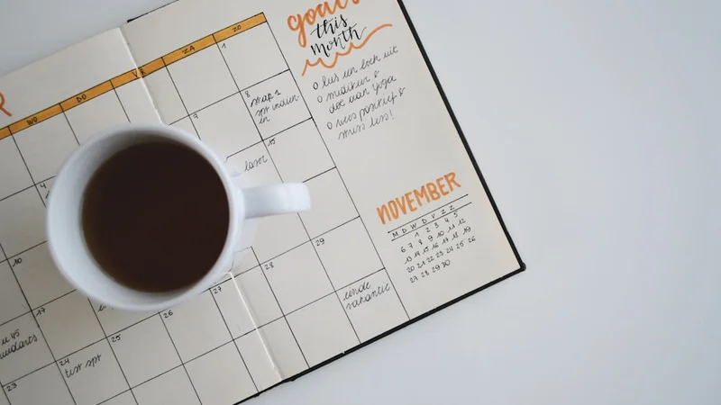 A weekly planner spread with handwritten goals, a pen, and a small cup of espresso on a minimalist wooden desk