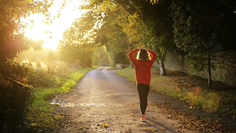 person running outdoors in early morning light along an empty path