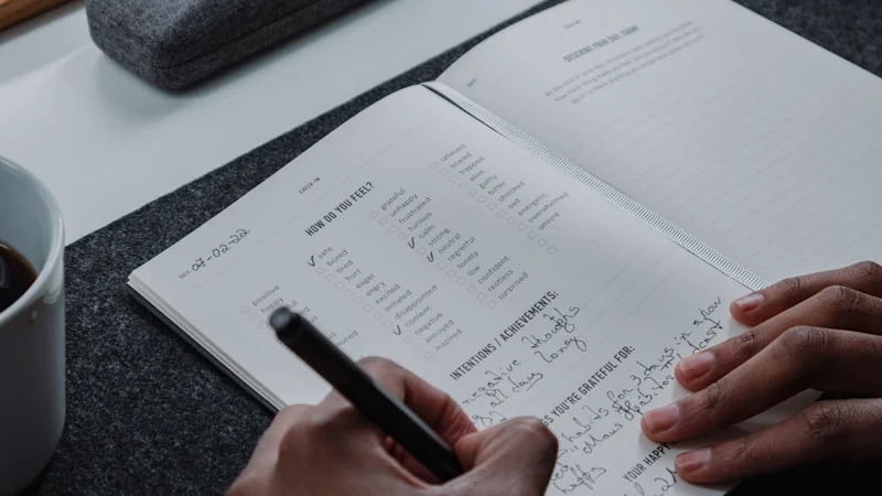 a clean desk with an open notebook and pen, representing deliberate habit design and self-knowledge