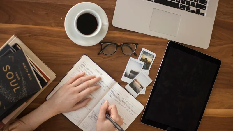 Person sitting at a desk writing a social network audit in a journal, with names and arrows visible on the open page