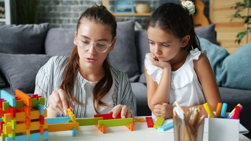 Primer plano de manos construyendo con piezas de LEGO de colores sobre una mesa de madera, iluminación cálida