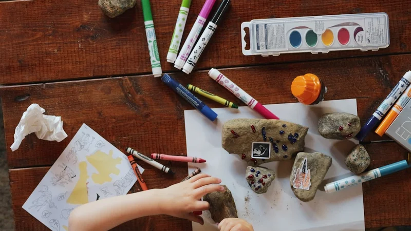 niño pequeño construyendo libremente con bloques de madera coloridos y abiertos, luz natural cálida, sin manual de instrucciones a la vista