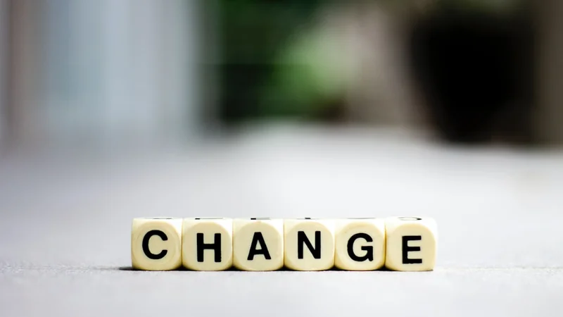 Vue de dessus d'un carnet ouvert et d'un stylo sur un bureau minimaliste, avec trois titres manuscrits : « Ce qui a changé », « Ce que j'actualise », « Ce que je fais » — la pratique du journal de changement