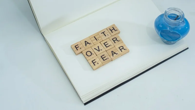 Une personne qui écrit dans un journal à un bureau avec une lumière matinale douce, pratiquant l'exercice de fear-setting avec trois colonnes visibles sur la page