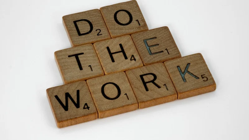 Spazio di lavoro domestico pulito e ben illuminato con pochi oggetti sulla scrivania — un quaderno, un bicchiere d'acqua, un'atmosfera concentrata