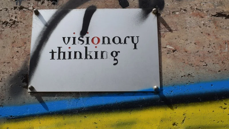 Uno spazio di lavoro pulito e minimalista con una vision board ben organizzata sulla parete che mostra obiettivi, immagini del processo e traguardi specifici