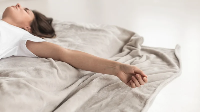 Pessoa sentada com as pernas cruzadas à luz da manhã, mãos nos joelhos, olhos fechados praticando respiração nasal