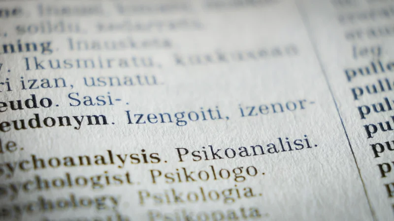 Pessoa sentada numa mesa tarde da noite olhando para o celular com expressão conflitada, luz quente de abajur, sombra suave