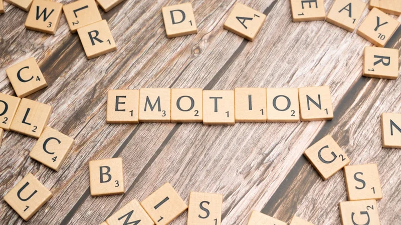 Close em um caderno aberto com rótulos emocionais escritos à mão em uma única palavra — palavras como "angústia", "aliviado", "frustrado" em letra clara, uma caneta ao lado, luz natural da janela