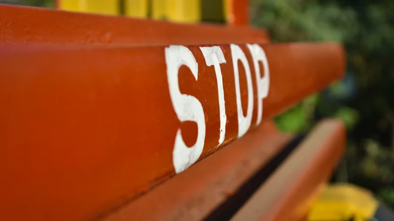 Uma pessoa parada em uma encruzilhada entre dois caminhos — um levando a uma multidão segurando placas de pontuação, o outro levando a um horizonte aberto — representando a escolha entre validação externa e crescimento autodirigido